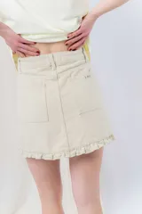 Minifalda de denim color crema con volados en los bolsillos delanteros y en el ruedo.