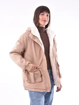 Campera color beige con interior de piel sintética blanca, capucha, cierre frontal con botones a presión, bolsillos laterales con solapa y puños elásticos.