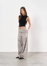 Pantalón baggy gris con estampado abstracto en tonos beige y blanco.