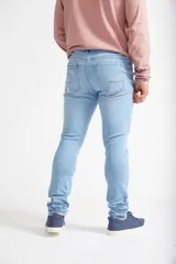 Jean skinny de hombre color negro, ajustado desde la cadera hasta los tobillos, con roturas en las rodillas y logo bordado en el bolsillo trasero.