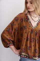 Camisa marrón con estampado floral y lentejuelas, escote en V y mangas largas abullonadas.