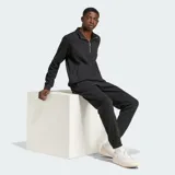 Buzo Adidas Essentials negro de corte clásico, cuello alto con cierre de medio largo, bolsillo tipo canguro y logo bordado en el pecho.