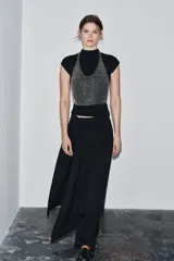 Top plateado de anillas metálicas con cuello halter y hombros descubiertos. Se cierra con mosquetón en cuello y espalda.