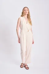 Mono largo color crudo de lino, con cuello en V, sin mangas, corte a la cintura con botón y pantalón de corte recto.