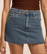 Minifalda de jean azul con bolsillos delanteros y traseros, cierre con botón y cremallera.