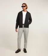 Campera negra de algodón con cuello inglés, cierre con cremallera, manga larga con ajuste fruncido elástico en el bajo trasero y bolsillos laterales.