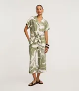 Pantalón tipo pantacourt confeccionado en viscosa con estampado de follaje verde sobre fondo blanco, con cintura elástica y diseño de pierna ancha y corta.
