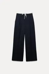 Pantalón ancho gris con textura de espiga, tiro alto, doble cintura elástica ajustable con cordón, pinzas frontales, bolsillos delanteros y falso bolsillo de vivo en la espalda.