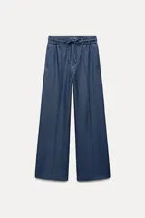 Pantalón de tiro alto azul denim, con cintura elástica ajustable con cordón, bolsillos laterales y traseros, y pernera ancha.