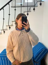 Sweater color beige tejido en lana simil cashmere, con cuello polo y cartera abotonada.