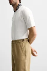 Pantalón chino color beige de corte recto, con cintura ajustable con cordón interior y trabillas laterales. Tiene bolsillos frontales y traseros de vivo.