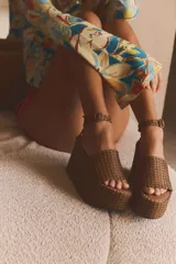 Sandalias con plataforma tipo cuña color marrón, con cuerpo trenzado, tira delantera y cierre mediante tira con hebilla a la pulsera del tobillo.