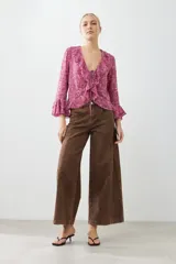 Blusa fucsia estampada con volados, escote en V y mangas largas acampanadas.