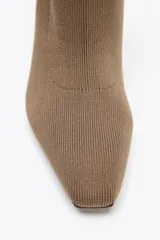 Botín de tacón color marrón, de tejido elástico con acabado en punta. El tacón es cuadrado y mide 7,5 cm de alto.