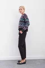 Pantalón negro de tiro alto con elástico interno en la cintura, botones falsos y terminación con volado. Tiene bolsillos aplicados en delantero y falsos en espalda.