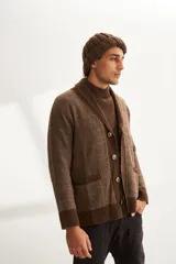 Cardigan tejido color marrón con cuello smoking, cierre con botones y bolsillos delanteros.