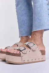 Sandalias beige con plataforma de corcho y doble tira con hebillas y tachas plateadas.
