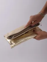 Sobre de mano color crema, con cierre de cremallera y tira de cuero para sujetar a la muñeca.