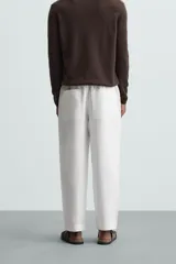 Pantalón negro de lino, corte recto y relaxed fit, con cintura elástica ajustable con cordón, bolsillos laterales y traseros.