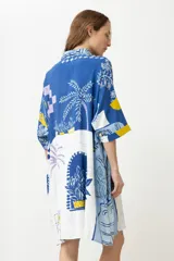 Vestido camisero corto con estampado de paisaje en tonos azules y amarillos.