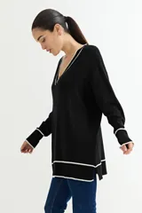 Sweater negro de tejido de punto con escote en V y ribetes blancos en cuello, puños y ruedo.
