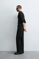 Pantalón de jean celeste de corte flare, con tiro medio, cinco bolsillos, cierre frontal con cremallera y botón, y bajo con acabado irregular.