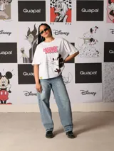 Remera blanca de corte oversize con estampado frontal de Mickey Mouse en movimiento y texto "Mickey Mouse" en rosa.