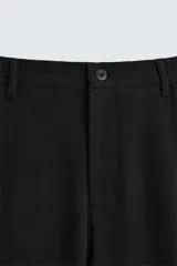 Pantalón negro de corte regular fit, con bolsillos laterales y bolsillos traseros de vivo. Presenta un bajo con vuelta y cierre frontal con cremallera y botón.
