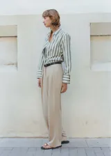 Pantalón de vestir color beige, de corte wide leg, tiro medio, con pinzas delanteras y cierre frontal con botón, gancho y cremallera.