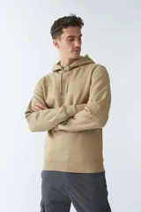 Buzo canguro color arena de felpa, con capucha ajustable, bolsillo tipo canguro, mangas largas y logo estampado en el pecho.