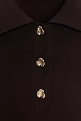 Top marrón de punto con cuello polo, manga corta y botones dorados en forma de flor.