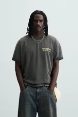 Camiseta negra con efecto lavado, cuello redondo, manga corta y estampado en el frente con la frase "Don't miss out! One Night. One Stage.".