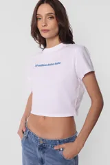 Remera blanca de jersey corte baby tee con cuello alto de ribb complemento. Estampa en delantero con la frase "30 million dolar babe" en color azul.