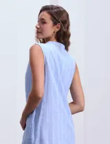Vestido corto de algodón a rayas verticales celestes y blancas, con cuello a la base y abertura central acordonada. Incluye forro interno.