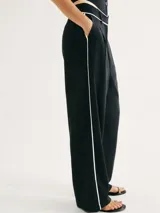 Pantalón negro de corte recto y tiro alto, con bolsillos laterales y detalle de ribete blanco en cintura y laterales.