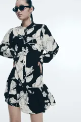 Vestido corto de viscosa con estampado floral en blanco y negro. Modelo de corte holgado con cuello mao, botones delanteros y mangas globo largas con abertura y botón en los puños. Costura fruncida en la pollera para un efecto evasé.