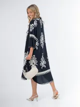 Vestido midi oversized con estampado en fondo negro, cuello tipo camisa, escote en V y tajos laterales.