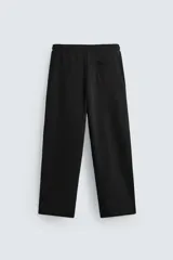 Pantalón jogger negro de corte ancho, confeccionado en tejido de algodón con interior de rizo. Cuenta con cintura elástica ajustable con cordón interior, bolsillos laterales y bolsillo trasero de parche.