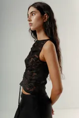 Top negro de encaje con escote cuadrado y tirantes anchos. Presenta un fruncido central ajustable mediante cordón.