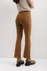 Pantalón jean marrón acampanado con detalle desflecado en el bajo y tiro medio.