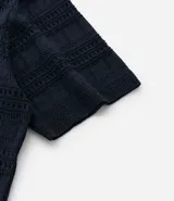 Remera polo de hombre color beige, con cuello en V, mangas cortas y textura patchwork calada.