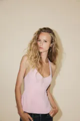 Top color rosa pálido, con cuello halter y escote en pico. Presenta un lazo en la espalda y cierre lateral con cremallera oculta.