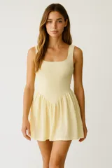 Vestido corto color amarillo pálido con textura arrugada, breteles anchos y escote cuadrado. Falda fruncida con corte en forma de V en la cintura.