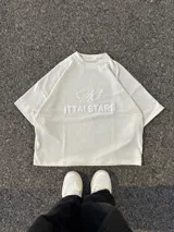 Remera celeste de corte holgado con cuello redondo y estampado en relieve con el logo de la marca y la frase "Ittai Stars".