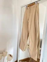 Pantalón de ecocuero rojo y beige, tiro alto y corte recto.