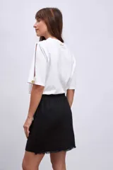 Minifalda color beige de corte evasé con diseño cruzado y detalle de flecos en el ruedo.