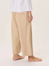 Pantalón ancho color beige claro, con corte holgado y costuras visibles en el frente de cada pierna.