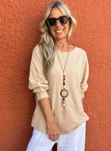 Buzo de manga larga color beige claro, con textura acanalada y corte holgado.