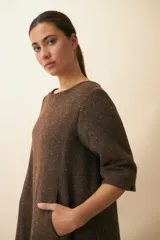 Vestido largo debajo de la rodilla, acampanado, color marrón, con cuello bote, bolsillos laterales y mangas 3/4 con detalle de tajo.