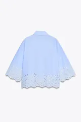 Camisa celeste de popelina con cuello solapa y manga ancha por debajo del codo. Bajo acabado con bordados perforados. Cierre frontal con botones.